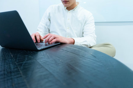 Mid section of businessman using laptop at desk in office. business and technology conceptの写真素材