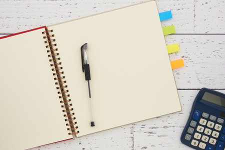 Notebook with pen and calculator on white wooden table, top viewの写真素材