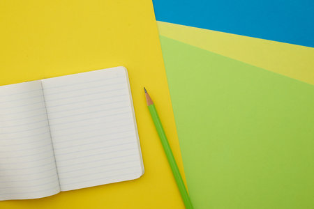 Pencil and notebook on colorful background. Top view with copy space