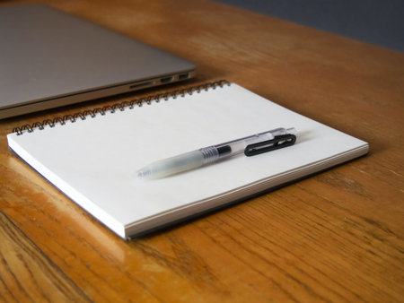 Notebook with pen and laptop on the wooden table, stock photo