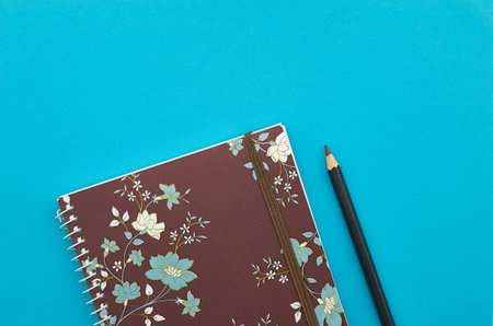 Notebook and pencil on blue background. Top view with copy spaceの写真素材