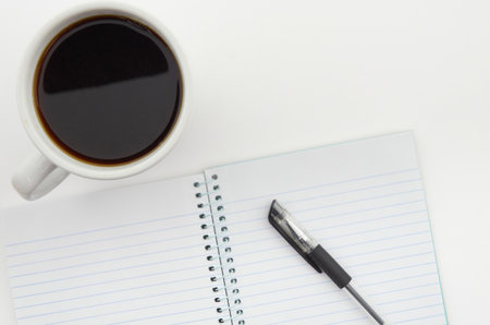 Blank notebook with pen and cup of coffee on white background.の写真素材