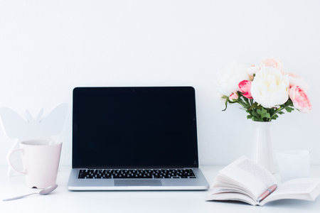 Laptop with blank screen and flowers in vase on white backgroundの写真素材