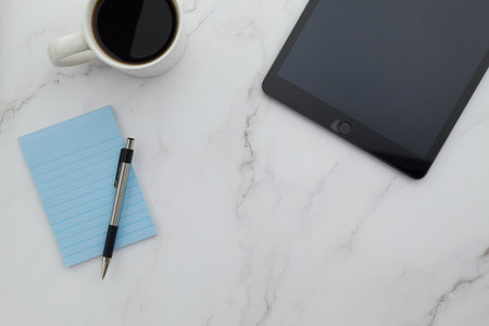 Office desk with tablet, coffee cup and notepadle background
