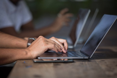 Close up of business people hands typing on laptop keyboard in coffee shop