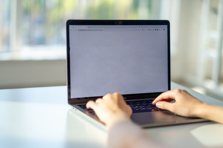 Close up of woman hands typing on laptop with blank white screen.の写真素材