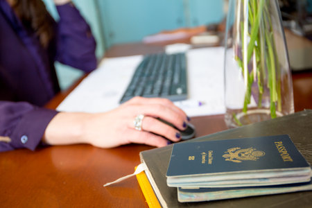 Close-up of a female hand holding a passport and a laptopの写真素材