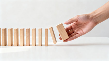 Hand stopping domino effect on white background. Risk management concept.の素材