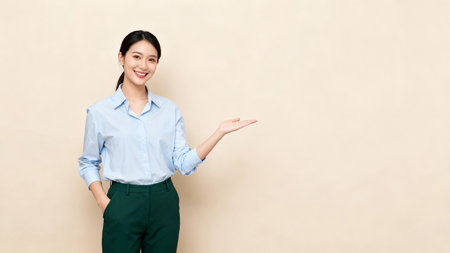 smiling asian businesswoman showing copy space on the palm of her handの素材