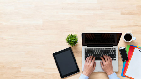Top view of businessman working with laptop and tablet computer on wooden deskの素材