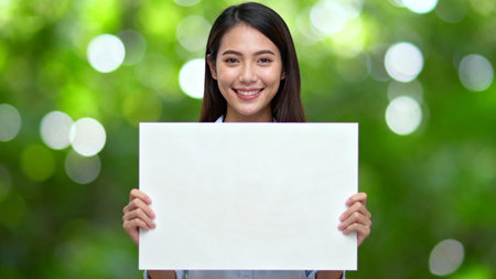Young asian woman holding a blank white board in front of her faceの素材