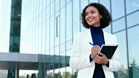Portrait of happy african american businesswoman writing in notebook outdoorsの素材