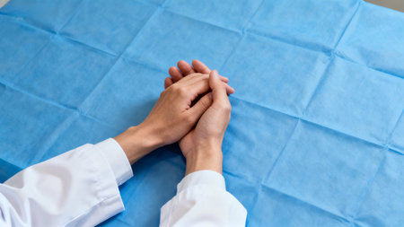Hands resting on blue medical sheetの素材