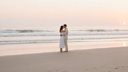 Young couple in love embracing and kissing on the beach at sunset.の素材