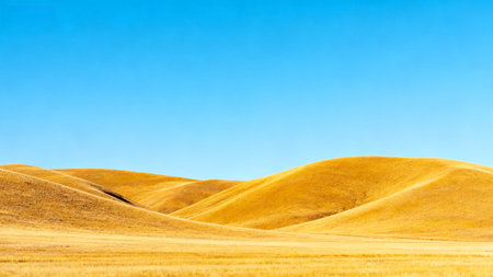 Golden rolling hills under blue skyの素材