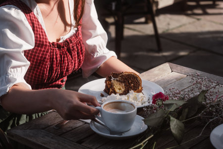 Woman in traditional bavarian clothes having a cup of coffee and cakeの写真素材