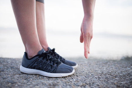 Woman tying shoelaces on her running shoes.の写真素材