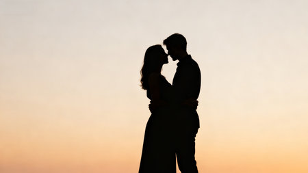 Silhouette of couple embracing at sunsetの素材