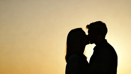 Silhouette of couple kissing at sunsetの素材