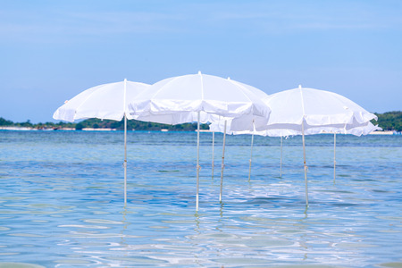 White umbrella on summer tropical beach with sailing boat.の写真素材