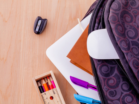 Backpack with school supplies laptop,book stationary,mouse,pen,ruler, and color pencil on wooden table .の写真素材