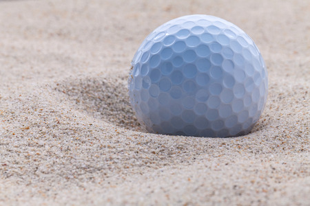 Close up golf ball in sand bunker shallow depth of field.の写真素材