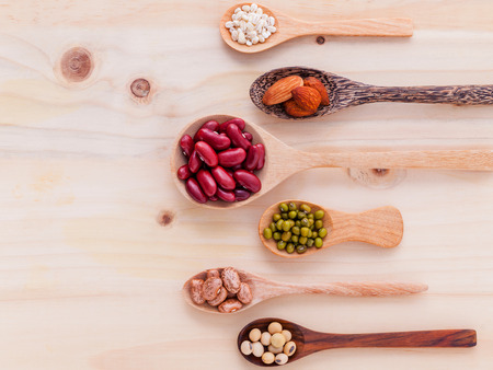 Assortment of beans and lentils in wooden spoon on wooden background. mung bean, groundnut, soybean, red kidney bean and almond.の写真素材