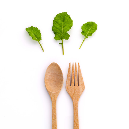 Healthy food concept fresh organic green leaves with wooden fork and spoon isolated on white background cutout .の写真素材