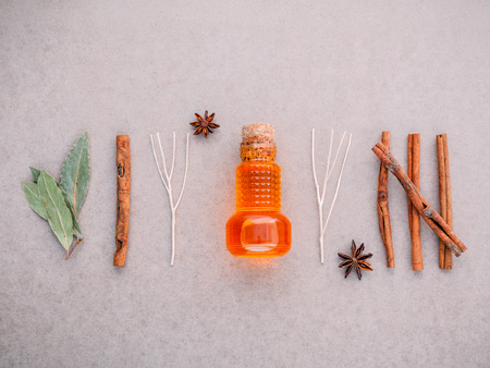 Bottle of essential oil with cinnamon stick ,star anise ,bay leaves  on brown background .