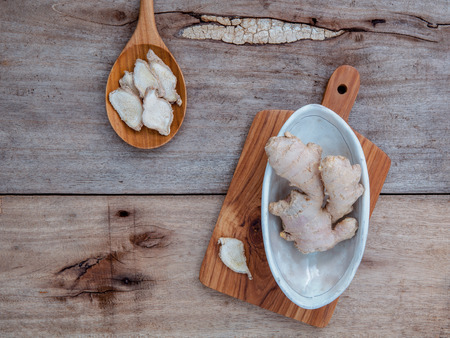 Alternative medicine and seasoning - Ginger root and dried ginger in wooden spoon set up on old wooden table.の写真素材