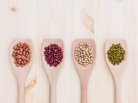 Assortment of beans and lentils in wooden spoon on wooden background.  soybean, mung bean , red bean and brown pinto beans .の写真素材