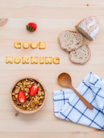 Good morning concept - Cereal in wooden bowl with strawberry and wooden spoon set up on wooden background.の写真素材