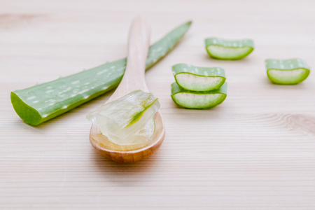 Alternative skin care  aloe vera gel in wooden spoons with aloe vera leaves set up on wooden table.の写真素材
