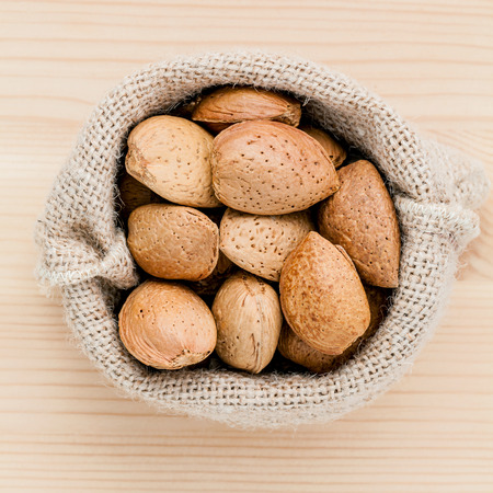 Almonds kernels and whole almonds on wooden background. Whole and chopped almond on wooden background. almond kernels and nutcracker. Selective focus depth of field.の写真素材