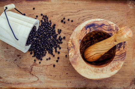 Closeup black pepper in wooden box with mortar and pestle on shabby teak wood table.の写真素材