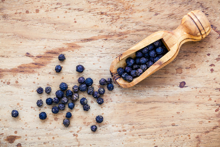 Closeup black pepper in wooden spoon on shabby teak wood table.の写真素材