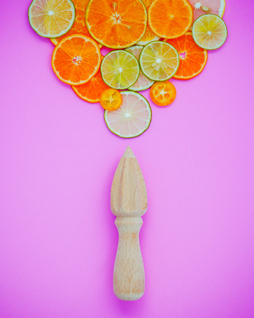 Mixed fresh citrus fruits and wooden juicer for summer citrus juice. Citrus fruits sliced lime,orange and lemon on light pink background flat lay.の写真素材
