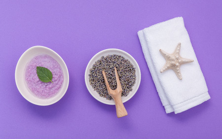 Homemade skin care lavender bath salt beauty treatment, towel and lavender flower on purple...