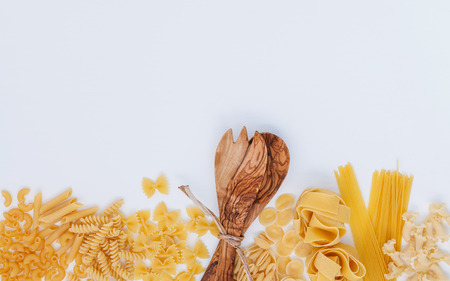 Italian foods concept and menu design. Various kind of Pasta Farfalle, Pasta A Riso, Orecchiette Pugliesi, Gnocco Sardo and Farfalle with wooden spatula setup on white wooden background with flat lay.の写真素材