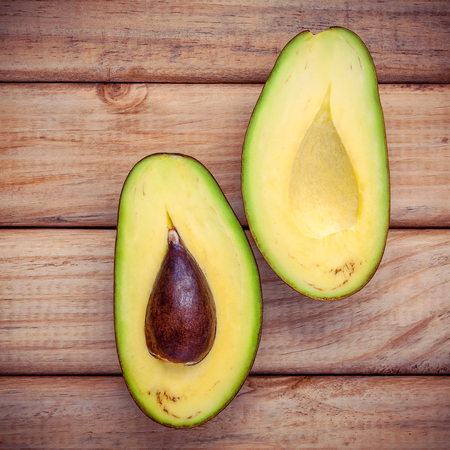 Food background with fresh organic avocado . Fresh cutting avocado on wooden background. Organic avocados for healthy food concept.の写真素材