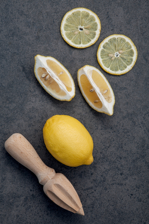 Fresh lemons and  lemons leaves on dark stone background. Fresh lemons and lemon slice on dark stone with flat lay.  Fresh citrus fruit background.の写真素材