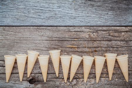 Flat lay ice cream cones collection on shabby wooden background . Blank crispy ice cream cone with copy space for sweets menu design.の写真素材