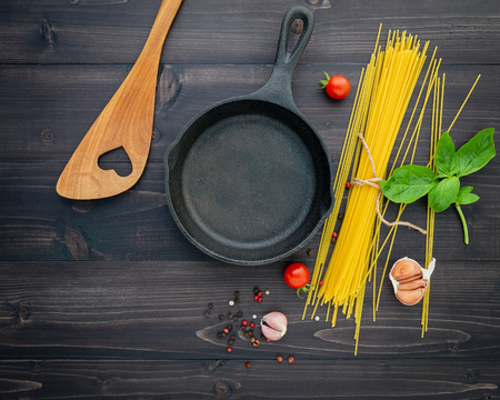 The thin spaghetti on black wooden background. Yellow italian pasta with ingredients. Italian food and menu concept.の写真素材