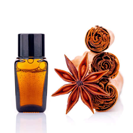 Cinnamon essential oil bottle with Ceylon cinnamon sticks and anise star isolated on white...