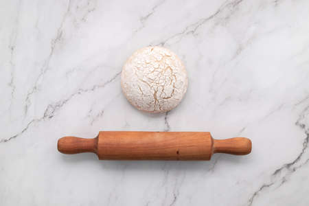 Fresh homemade yeast dough resting on marble table flat lay with rolling pin.の写真素材