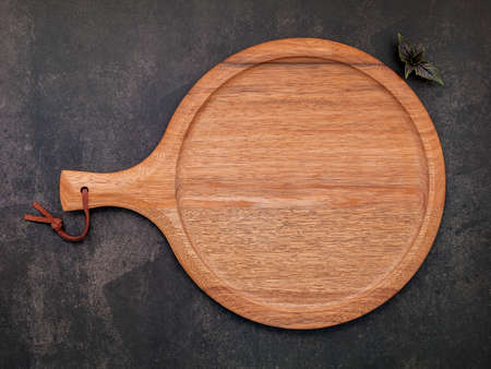 Empty wooden pizza platter set up on dark concrete. Pizza tray on dark concrete background flat lay and copy space.の写真素材