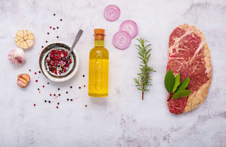 Raw Striplion Steak set up on white concrete background. Flat Lay of fresh raw beef steak with rosemary and spice on white shabby concrete background top view.の写真素材