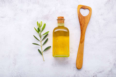 Glass bottle of olive oil and olive branch set up on white concrete background.の写真素材