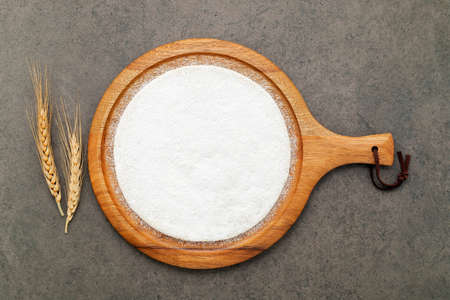 Thin homemade pizza dough with wheat ears  set up on dark concrete background.の写真素材