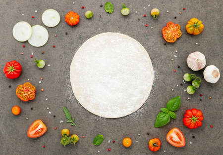 The ingredients for homemade pizza set up on dark stone background.の写真素材